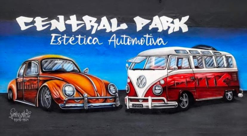 Uma parede pintada com uma imagem de um Fusca laranja, acompanhado de uma Kombi vermelha e branca. O fundo é azul, gradualmente se transformando em preto. No topo da imagem, está escrito 'Central Park'.
